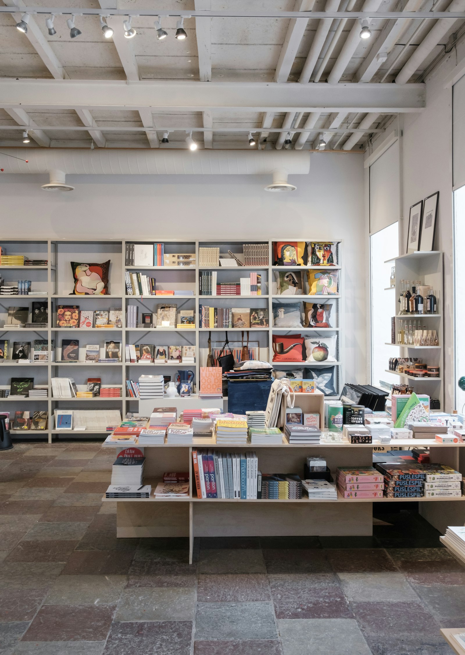 A bright bookshop with art and design titles on pale shelves and a central table (placeholder photo)